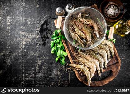Raw shrimp in a colander and on a cutting board. On a black background. High quality photo. Raw shrimp in a colander and on a cutting board.