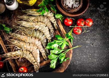 Raw shrimp on a cutting board with herbs and spices. On a black background. High quality photo. Raw shrimp on a cutting board with herbs and spices.