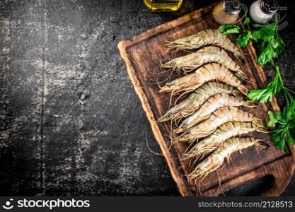 Raw shrimp on a cutting board with spices and parsley. On a black background. High quality photo. Raw shrimp on a cutting board with spices and parsley.