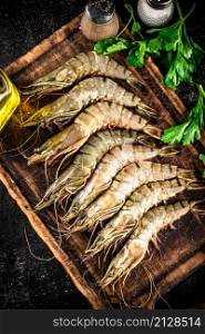 Raw shrimp on a cutting board with spices and parsley. On a black background. High quality photo. Raw shrimp on a cutting board with spices and parsley.