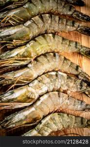 Raw shrimp on a wooden background. High quality photo. Raw shrimp on a wooden background.