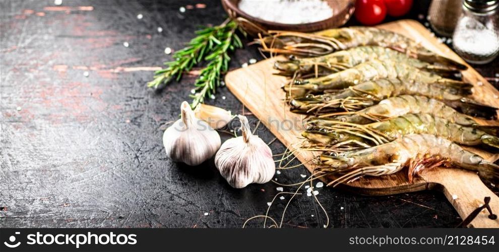 Raw shrimp on a wooden cutting board with tomatoes and spices. Against a dark background. High quality photo. Raw shrimp on a wooden cutting board with tomatoes and spices.