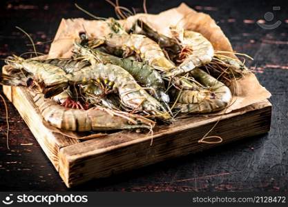 Raw shrimp on a wooden tray. Against a dark background. High quality photo. Raw shrimp on a wooden tray.