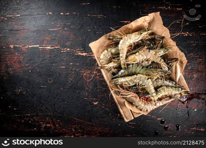 Raw shrimp on a wooden tray. Against a dark background. High quality photo. Raw shrimp on a wooden tray.