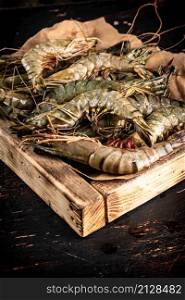 Raw shrimp on a wooden tray. Against a dark background. High quality photo. Raw shrimp on a wooden tray.