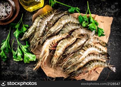 Raw shrimp on paper with spices and parsley. On a black background. High quality photo. Raw shrimp on paper with spices and parsley.