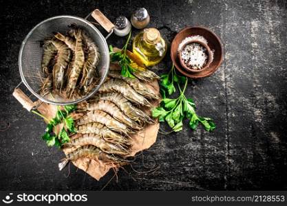 Raw shrimp on paper with spices and parsley. On a black background. High quality photo. Raw shrimp on paper with spices and parsley.