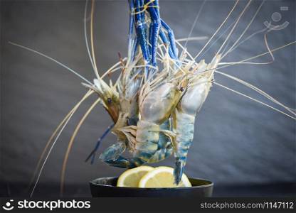 Raw shrimps on bowl with spices lemon on the dark plate background / fresh shrimp prawns for cooked food at restaurant or seafood market