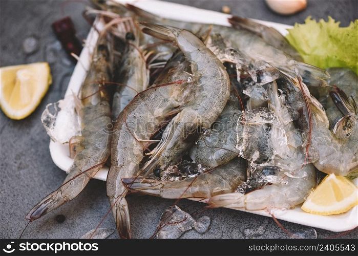 Raw shrimps on plate plastic tray, Fresh shrimp prawns for cooking with spices lemon vegetable salad lettuce on dark background in the seafood restaurant