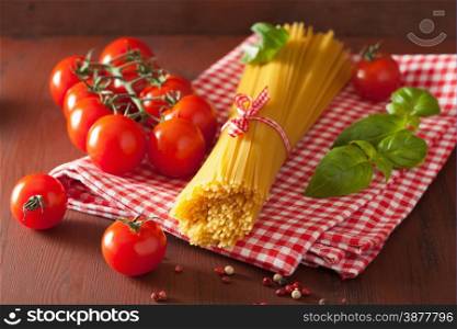 raw spaghetti pasta basill tomatoes. italian cuisine in rustic kitchen