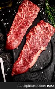 Raw steak on a cutting board. On a black background. High quality photo. Raw steak on a cutting board.