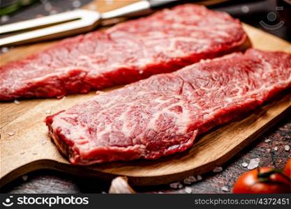 Raw steak on a cutting board. On a rustic dark background. High quality photo. Raw steak on a cutting board.