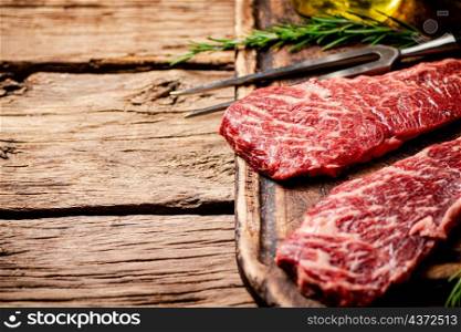 Raw steak on a cutting board. On a wooden background. High quality photo. Raw steak on a cutting board.