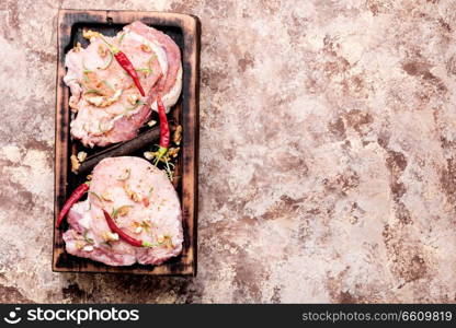 Raw steak on a cutting board with pepper,walnut and spices.. Two pieces of raw pork