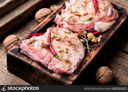 Raw steak on a cutting board with pepper,walnut.Raw pork meat.. Two pieces of raw pork