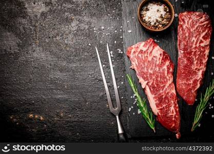 Raw steak on a stone board. On a black background. High quality photo. Raw steak on a stone board. On a black background.