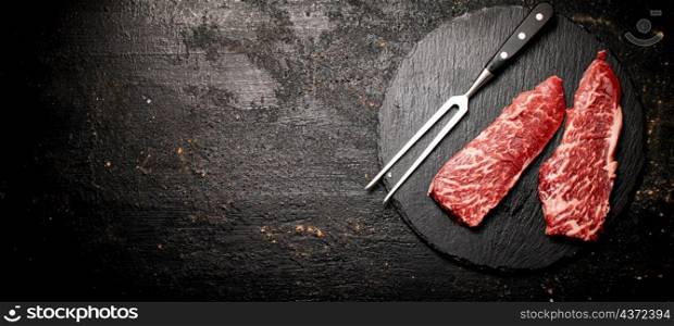 Raw steak on a stone board. On a black background. High quality photo. Raw steak on a stone board. On a black background.