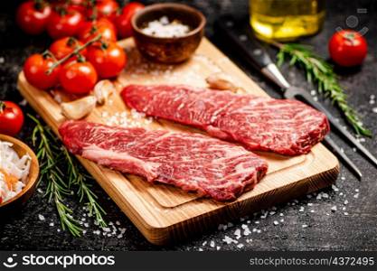 Raw steak on a wooden cutting board. On a black background. High quality photo. Raw steak on a wooden cutting board.