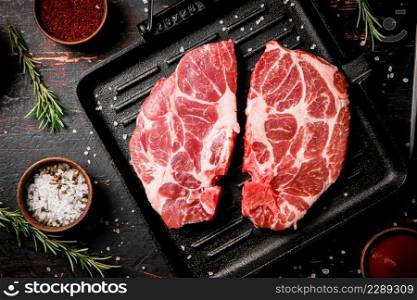 Raw steak pork in a grill pan with tomato sauce and spices. Against a dark background. High quality photo. Raw steak pork in a grill pan with tomato sauce and spices.