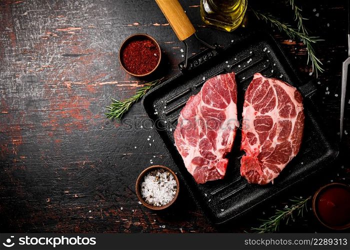 Raw steak pork in a grill pan with tomato sauce and spices. Against a dark background. High quality photo. Raw steak pork in a grill pan with tomato sauce and spices.