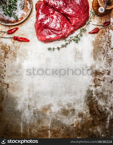 Raw steak with herbs and spices on rustic metal background, top view, place for text