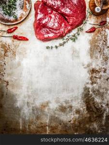 Raw steak with herbs and spices on rustic metal background, top view, place for text