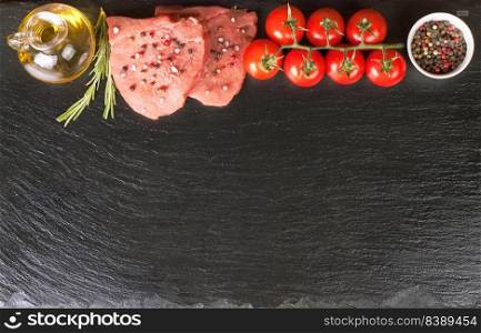 Raw steak with spices and ingredients for cooking on black slate surface. Free space for text. Flat lay. Top view. Raw steak with spices and ingredients for cooking. Flat lay. Top view.