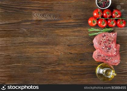 Raw steak with spices and ingredients for cooking on brown wooden surface. Free space for text. Flat lay. Top view. Raw steak with spices and ingredients for cooking. Flat lay. Top view.
