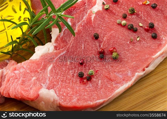 raw T-bone with rosemary and pepper
