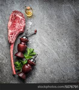Raw tomahawk beef steak , preparation for grill or cooking on dark rustic concrete background, top view, place for text