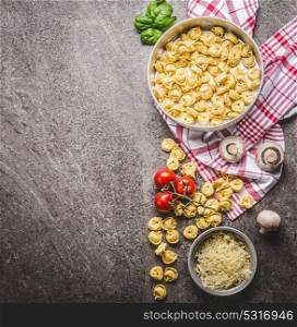 Raw tortellini pasta in bowl with ingredients, ready for cooking on rustic background , top view . Italian cuisine food concept