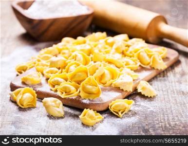 raw tortellini with flour on wooden table