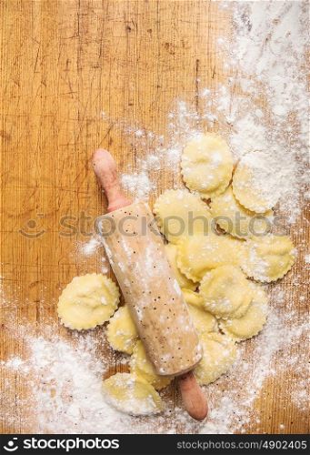 Raw Tortellini with Rolling pin on wooden background with wheat flour, top view