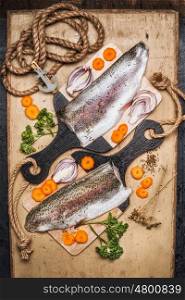 Raw trout fillet on cutting board with gut vegetables, top view. Healthy food and diet cooking concept