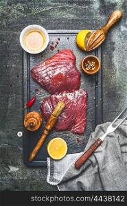 Raw tuna fish steak marinating with oil,lemon and rub brush on cutting board , top view, rustic background, dark styled.