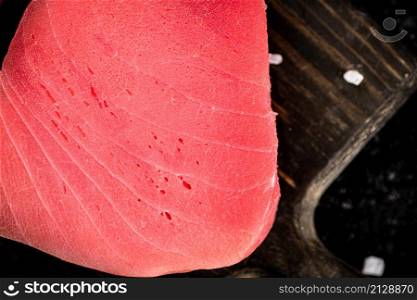 Raw tuna on a cutting board. On a black background. High quality photo. Raw tuna on a cutting board.
