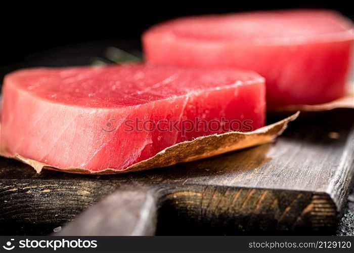 Raw tuna steak on a cutting board. On a black background. High quality photo. Raw tuna steak on a cutting board.