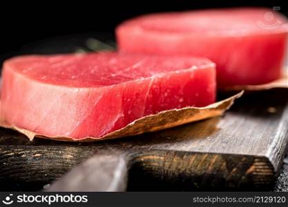 Raw tuna steak on a cutting board. On a black background. High quality photo. Raw tuna steak on a cutting board.