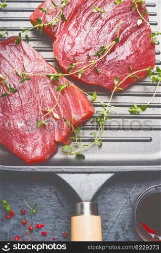 Raw Tuna Steaks in grill frying pan with herbs , top view, close up