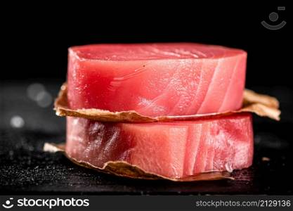 Raw tuna steaks on the table. On a black background. High quality photo. Raw tuna steaks on the table.