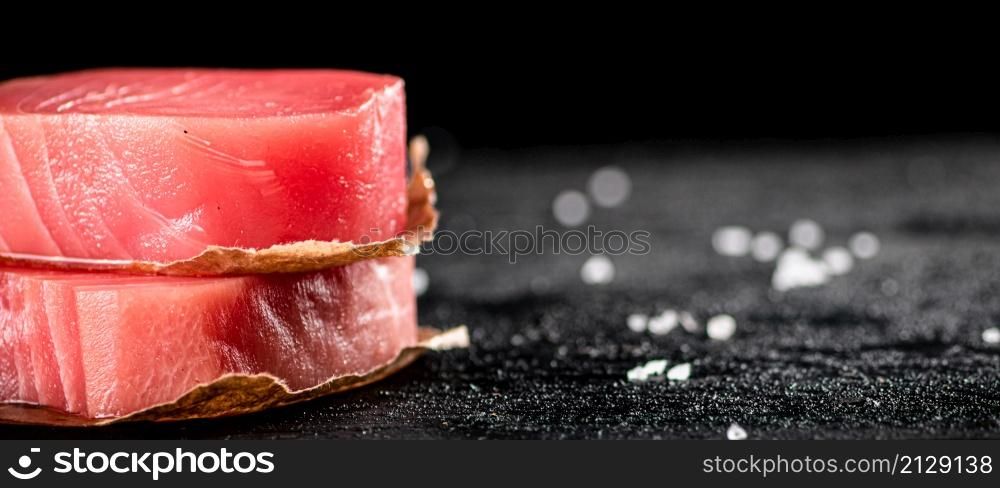 Raw tuna steaks on the table. On a black background. High quality photo. Raw tuna steaks on the table.