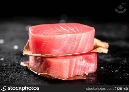 Raw tuna steaks on the table. On a black background. High quality photo. Raw tuna steaks on the table.