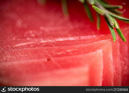 Raw tuna with a sprig of rosemary. Macro background. Tuna texture. High quality photo. Raw tuna with a sprig of rosemary.