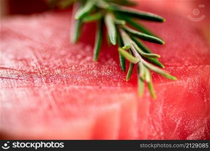 Raw tuna with a sprig of rosemary. Macro background. Tuna texture. High quality photo. Raw tuna with a sprig of rosemary.