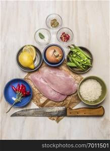 raw turkey on paper with knife lemon meat onion peas salt pepper on wooden rustic background top view
