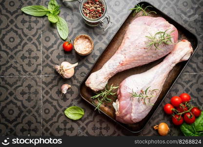 Raw turkey thigh with spices on a dark board, top view. Raw turkey thigh