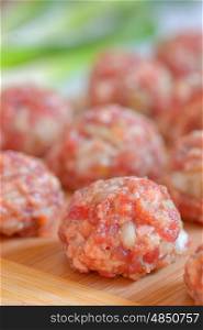 Raw Uncooked Meatballs on wooden plate
