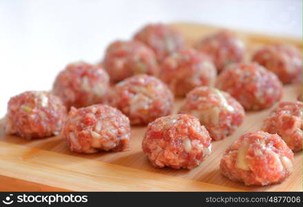 Raw Uncooked Meatballs on wooden plate