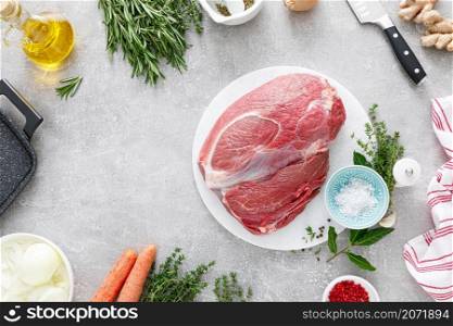 Raw veal meat fillet on kitchen cutting board with ingredients for cooking, top view, overhead, flat lay