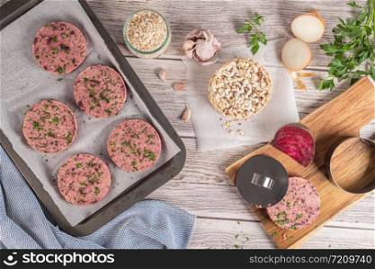 Raw veggie burger with beetroot and white beans with parsley leaves on wood cutting board